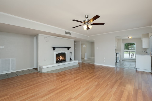 unfurnished living room with ceiling fan, light wood-type flooring, and sink