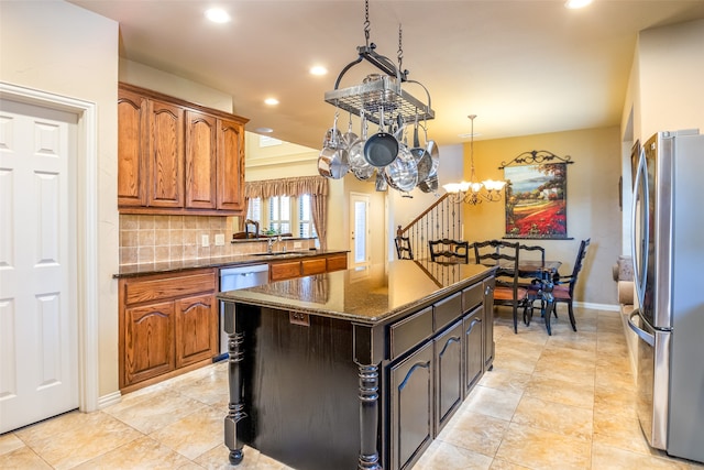 kitchen with sink, a kitchen island, backsplash, appliances with stainless steel finishes, and dark stone countertops