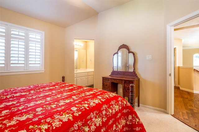 bedroom featuring light hardwood / wood-style flooring, lofted ceiling, ensuite bath, and multiple windows