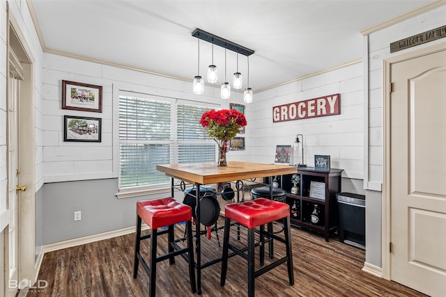 dining area with wood-type flooring, crown molding, and wood walls