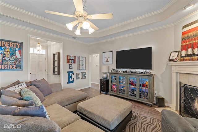 living room featuring ceiling fan, a fireplace, ornamental molding, and wood-type flooring