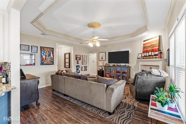 living room featuring a tray ceiling, ceiling fan, and dark hardwood / wood-style flooring