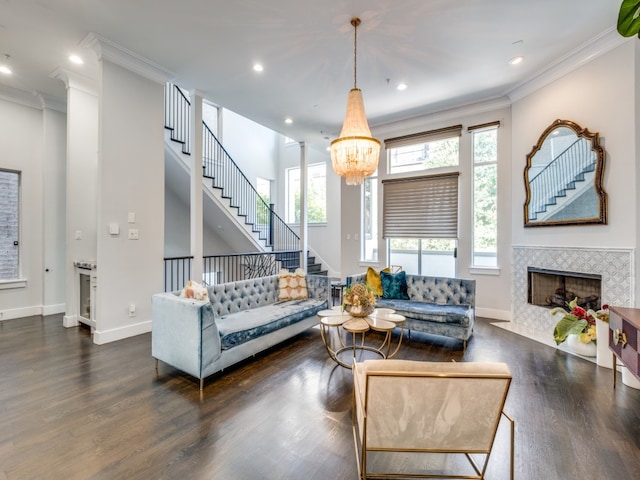 living room with a tile fireplace, ornamental molding, dark hardwood / wood-style floors, and a notable chandelier