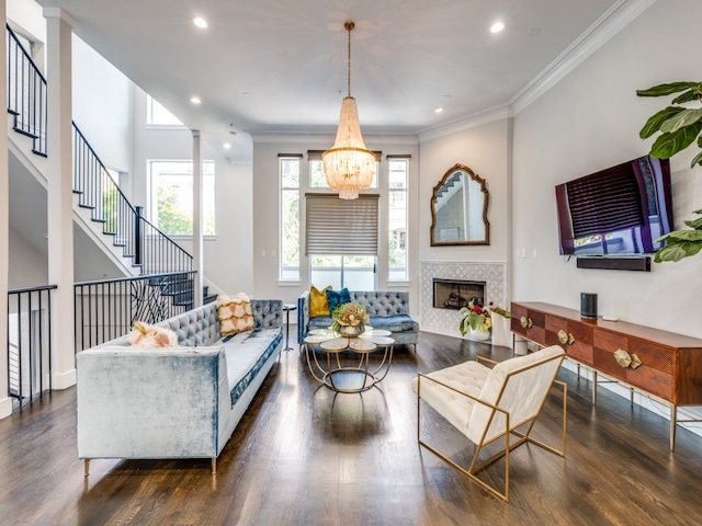 living room with a tile fireplace, crown molding, an inviting chandelier, and dark wood-type flooring