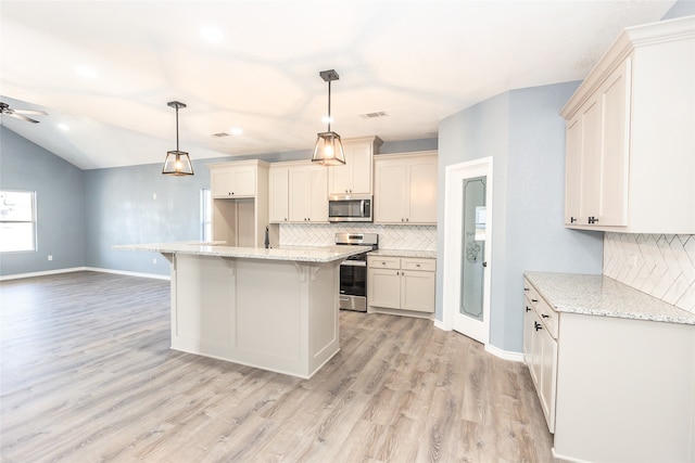 kitchen featuring light hardwood / wood-style floors, hanging light fixtures, a kitchen island, stainless steel appliances, and ceiling fan