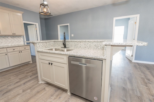 kitchen featuring light hardwood / wood-style floors, sink, cream cabinetry, a center island with sink, and stainless steel dishwasher