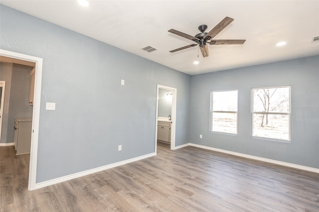 unfurnished bedroom with light wood-type flooring, ensuite bath, and ceiling fan