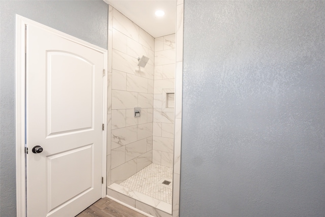 bathroom with wood-type flooring and a tile shower