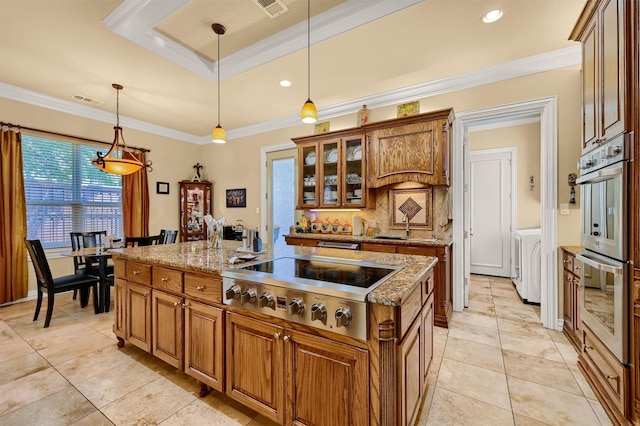 kitchen featuring ornamental molding, stainless steel appliances, a center island with sink, decorative light fixtures, and light stone countertops