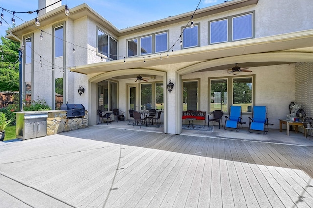 back of property featuring ceiling fan, a deck, a patio area, and exterior kitchen