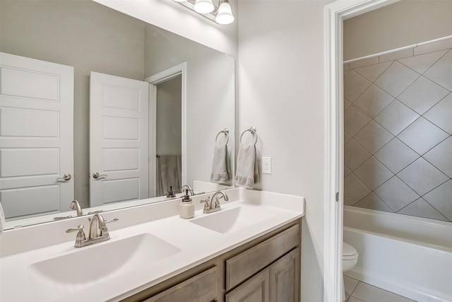 full bathroom featuring tiled shower / bath, vanity, toilet, and tile patterned floors