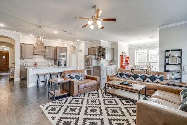 living room with ceiling fan with notable chandelier, crown molding, and dark hardwood / wood-style flooring