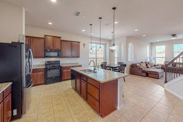 kitchen with a center island with sink, sink, black appliances, and a wealth of natural light