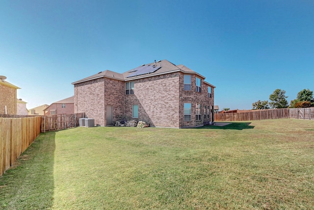 rear view of property featuring a lawn and central AC unit