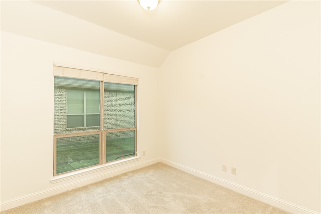 carpeted spare room with vaulted ceiling