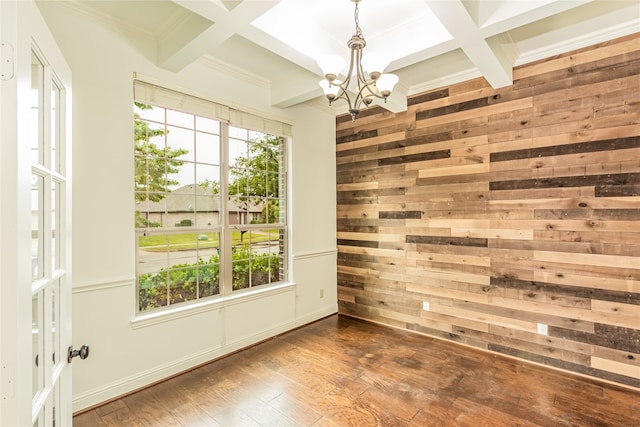 spare room with beam ceiling, coffered ceiling, an inviting chandelier, crown molding, and hardwood / wood-style floors