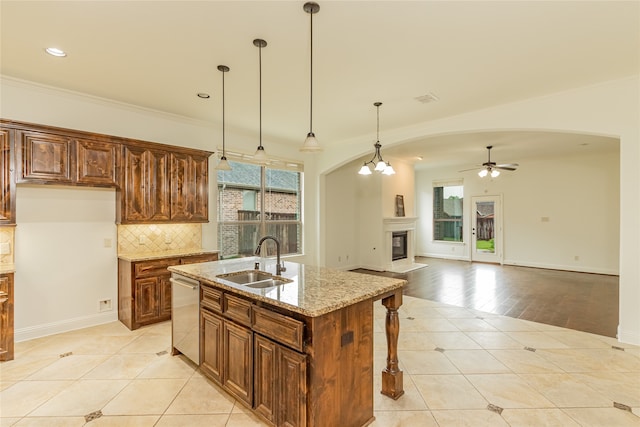 kitchen featuring sink, stainless steel dishwasher, light stone countertops, an island with sink, and light tile patterned floors