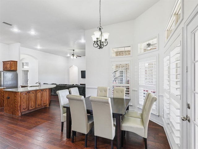 dining area featuring sink, ceiling fan with notable chandelier, and dark wood-type flooring