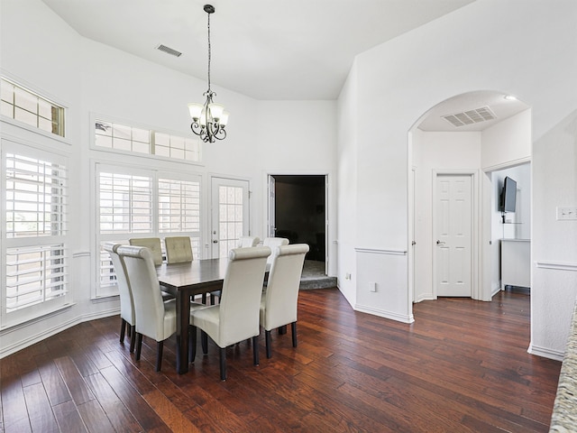 dining area with an inviting chandelier, dark hardwood / wood-style flooring, and a high ceiling