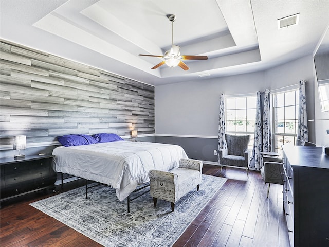 bedroom featuring ceiling fan, a tray ceiling, and dark hardwood / wood-style floors