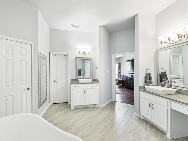 bathroom featuring a textured ceiling, a bath, hardwood / wood-style flooring, and vanity