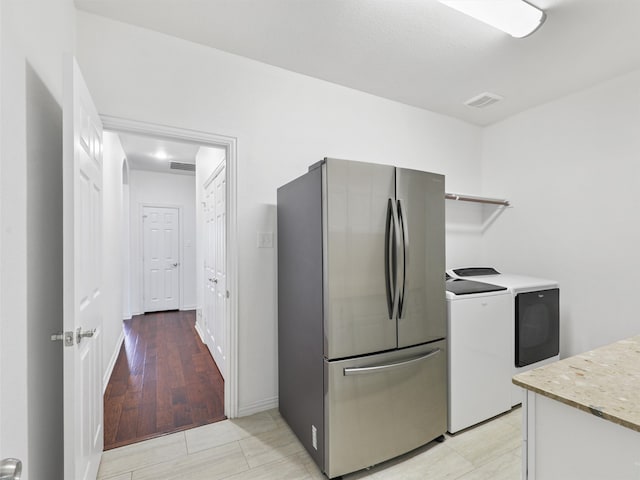 kitchen featuring stainless steel fridge, light hardwood / wood-style floors, and washer and dryer