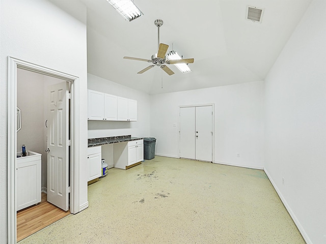 kitchen featuring ceiling fan, built in desk, and white cabinetry