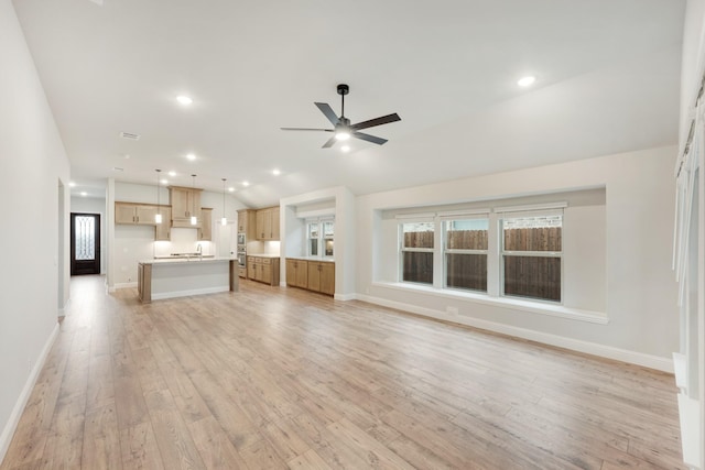 unfurnished living room featuring vaulted ceiling, light hardwood / wood-style flooring, ceiling fan, and sink