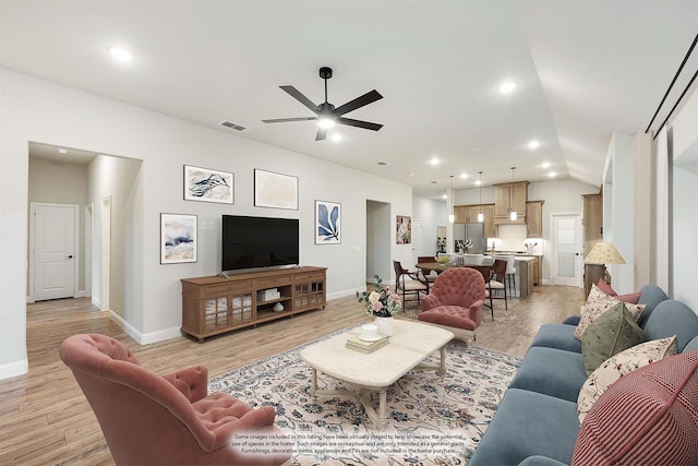 living room featuring ceiling fan, light wood-type flooring, and vaulted ceiling