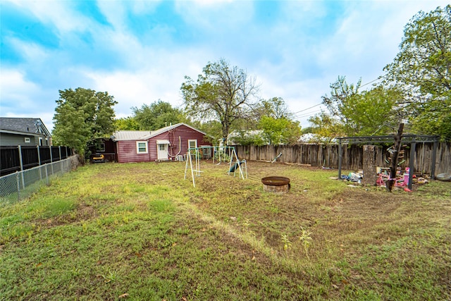 view of yard featuring a playground, an outbuilding, and an outdoor fire pit