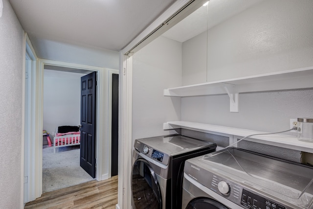 clothes washing area featuring light hardwood / wood-style flooring and washer and dryer