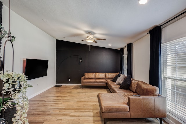 living room with lofted ceiling, ceiling fan, light hardwood / wood-style floors, and a textured ceiling