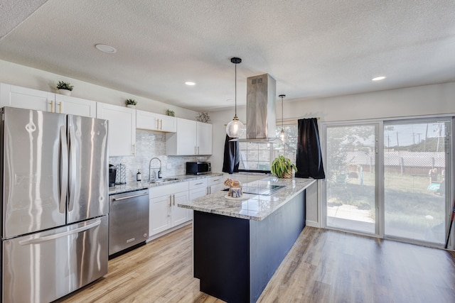 kitchen featuring appliances with stainless steel finishes, white cabinetry, light stone counters, island range hood, and light hardwood / wood-style flooring