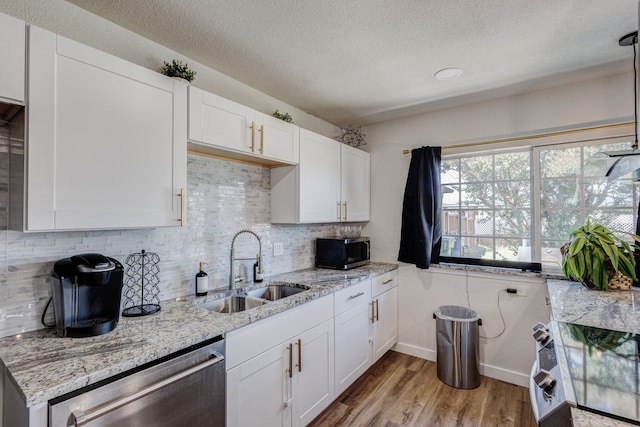 kitchen with light hardwood / wood-style floors, stainless steel appliances, sink, and white cabinetry