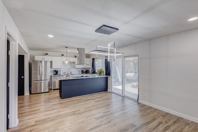 kitchen featuring white cabinetry, kitchen peninsula, island range hood, hanging light fixtures, and appliances with stainless steel finishes