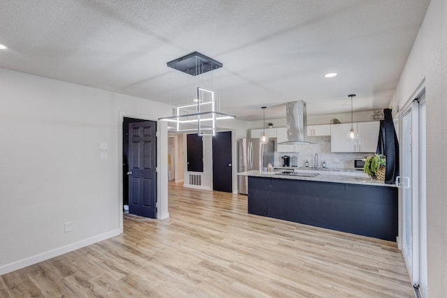 kitchen with pendant lighting, light hardwood / wood-style flooring, extractor fan, white cabinetry, and stainless steel appliances