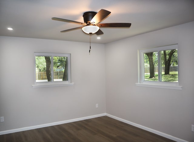 unfurnished room with ceiling fan, plenty of natural light, and dark wood-type flooring