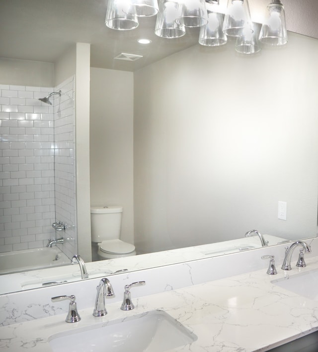 full bathroom with vanity, tiled shower / bath combo, and toilet