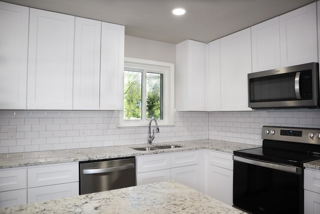 kitchen with appliances with stainless steel finishes, decorative backsplash, white cabinetry, and sink