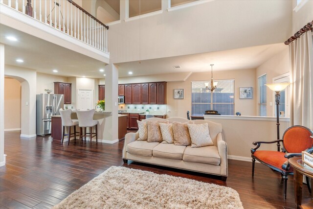 living room featuring dark hardwood / wood-style flooring, a towering ceiling, and a notable chandelier