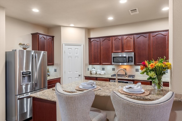 kitchen featuring a center island, stainless steel appliances, light stone counters, and backsplash