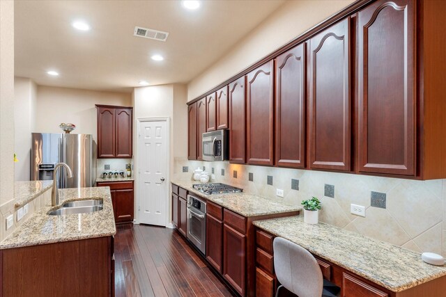 kitchen featuring decorative backsplash, light stone counters, stainless steel appliances, sink, and dark hardwood / wood-style floors