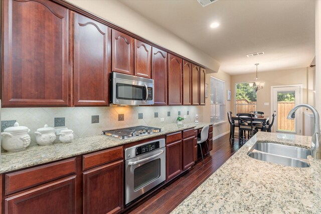 kitchen featuring sink, stainless steel appliances, dark hardwood / wood-style floors, a notable chandelier, and pendant lighting