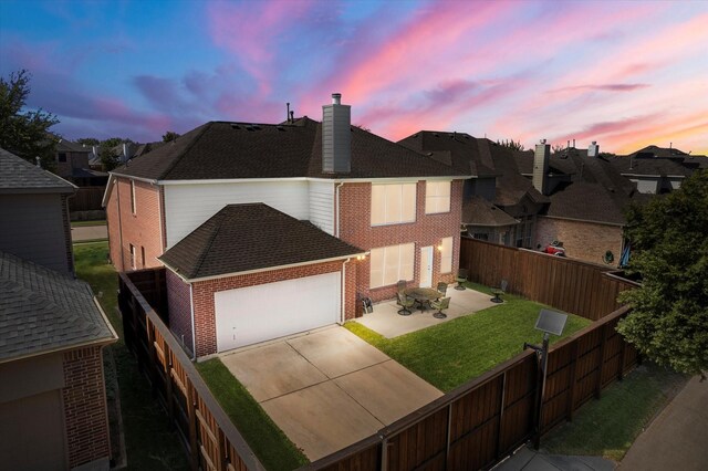 view of front facade featuring a patio, a garage, and a lawn