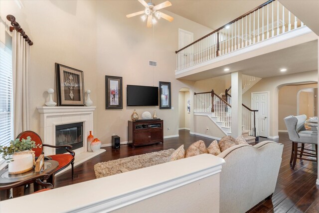 living room with ceiling fan, dark wood-type flooring, and a high ceiling