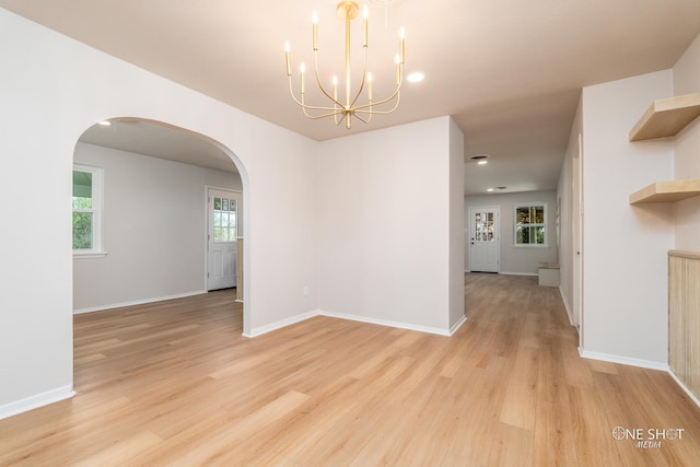 spare room with light hardwood / wood-style floors and a notable chandelier