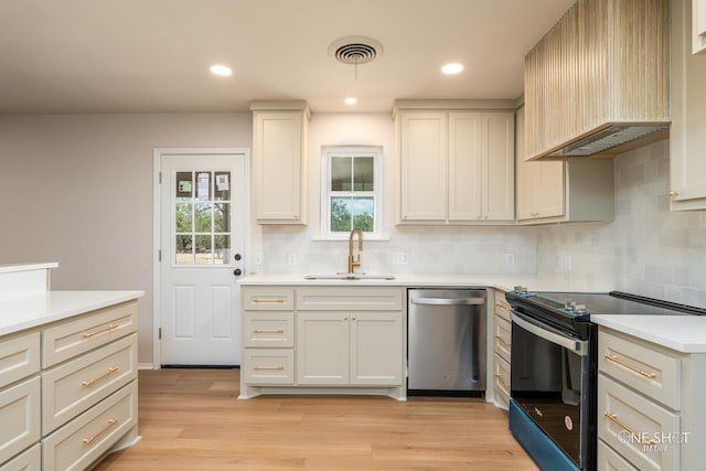 kitchen featuring black electric range oven, sink, stainless steel dishwasher, light hardwood / wood-style floors, and decorative backsplash