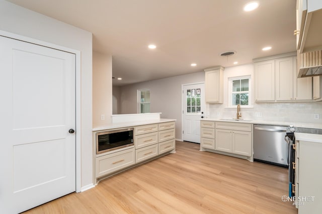 kitchen featuring light wood-type flooring, sink, stainless steel appliances, and tasteful backsplash