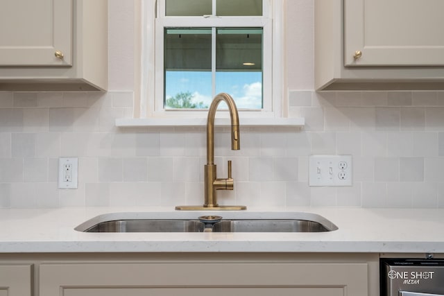 kitchen with light stone countertops, backsplash, white cabinetry, and sink