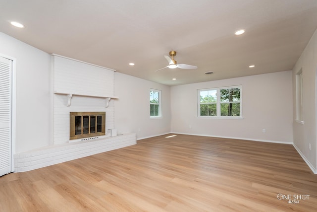 unfurnished living room with light hardwood / wood-style flooring, a brick fireplace, and ceiling fan